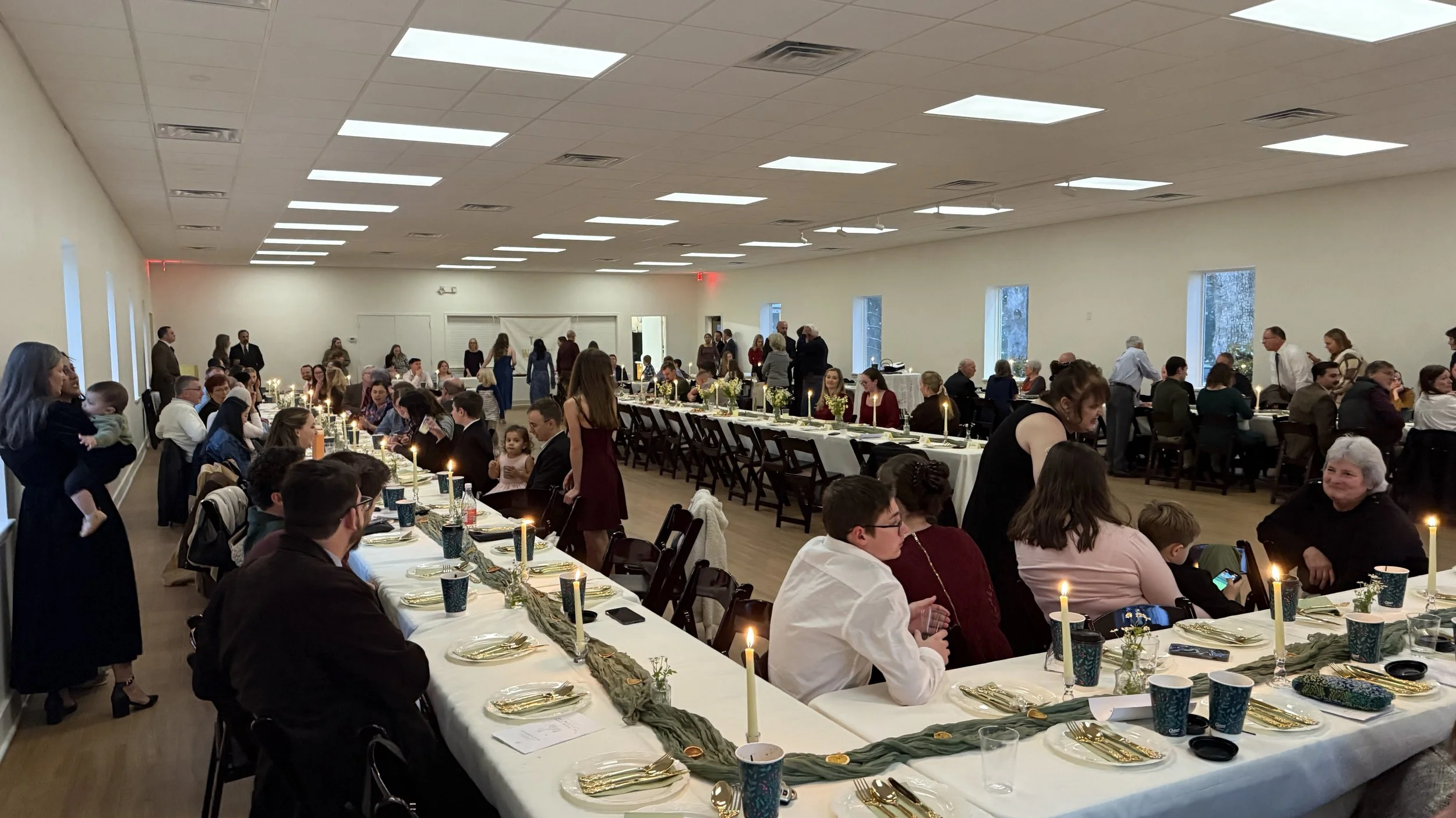 Church members seated at long tables in the expanded fellowship hall for a shared meal